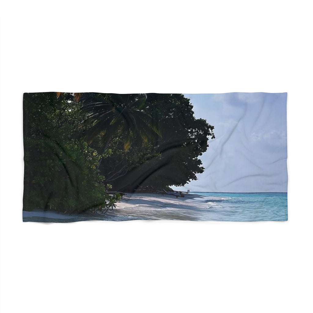 Shady Shoreline beach towel laid flat: dark green branches over a white-sand beach with turquoise water and pale sky
